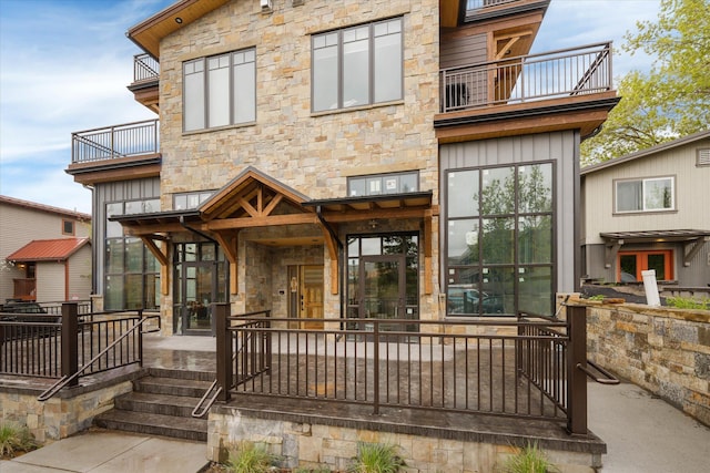 back of property featuring a balcony and stone siding