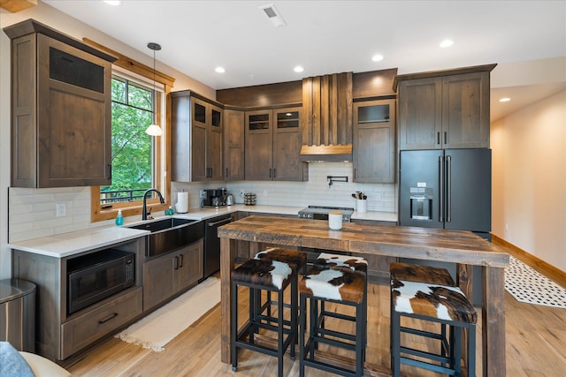 kitchen with black appliances, a sink, dark brown cabinets, light wood-style floors, and recessed lighting