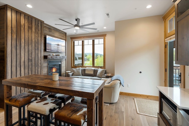 dining area with a fireplace, ceiling fan, baseboards, light wood-style floors, and recessed lighting