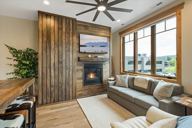 living area featuring a ceiling fan, light wood finished floors, a large fireplace, and recessed lighting