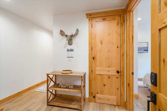 hall featuring light wood-style flooring and baseboards