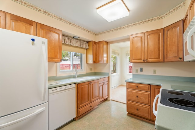 kitchen featuring white appliances, a sink, light countertops, and brown cabinetry