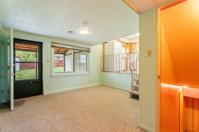 empty room featuring carpet floors, stairs, and baseboards
