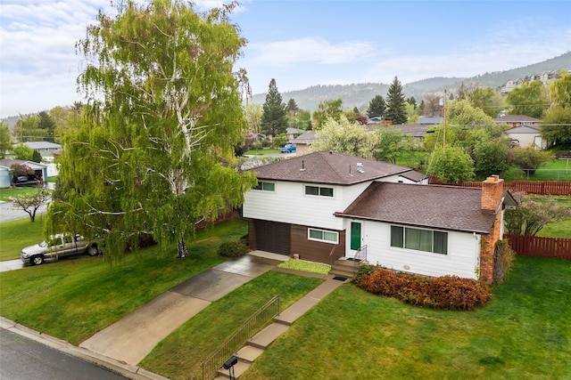 traditional-style home with an attached garage, concrete driveway, a mountain view, and a residential view
