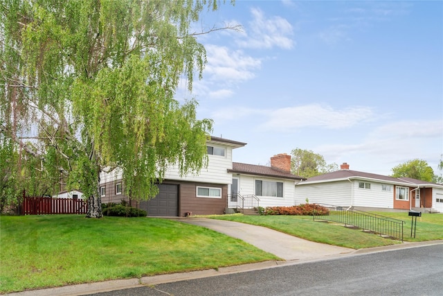 split level home featuring driveway, an attached garage, and a chimney