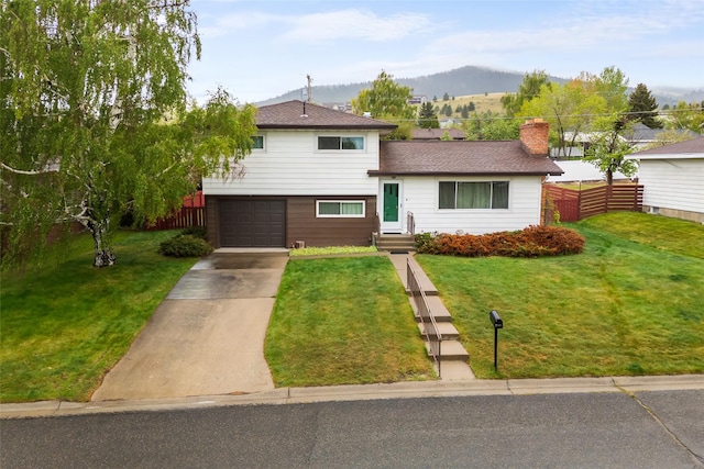 split level home featuring driveway, a garage, a mountain view, a chimney, and entry steps