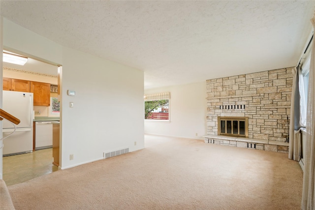 unfurnished living room featuring light carpet, a fireplace, a textured ceiling, and baseboards
