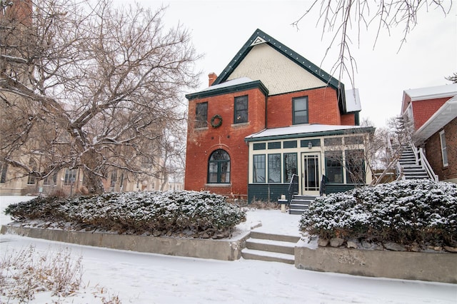 view of front of house with a sunroom, stairway, and brick siding