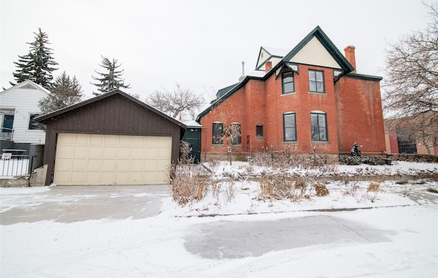 view of snowy exterior with a chimney and a garage