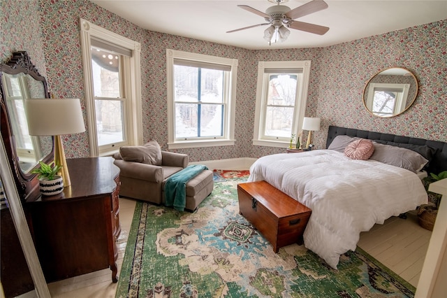 bedroom featuring wallpapered walls, light wood-style floors, and a ceiling fan
