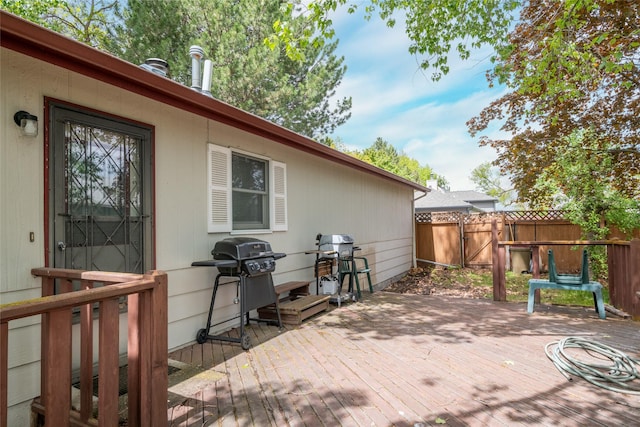 deck featuring area for grilling, fence, and a gate