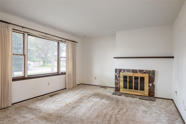 unfurnished living room featuring carpet flooring and a stone fireplace