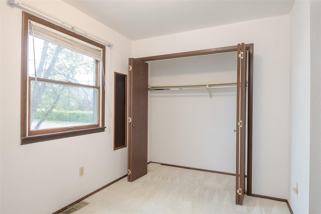 unfurnished bedroom with light carpet, a closet, and baseboards