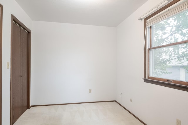 unfurnished bedroom with light colored carpet, baseboards, and a closet