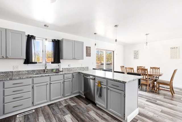 kitchen featuring dishwasher, a sink, gray cabinetry, a peninsula, and dark wood-style flooring