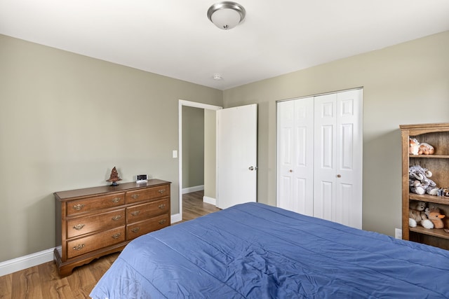 bedroom with baseboards, wood finished floors, and a closet