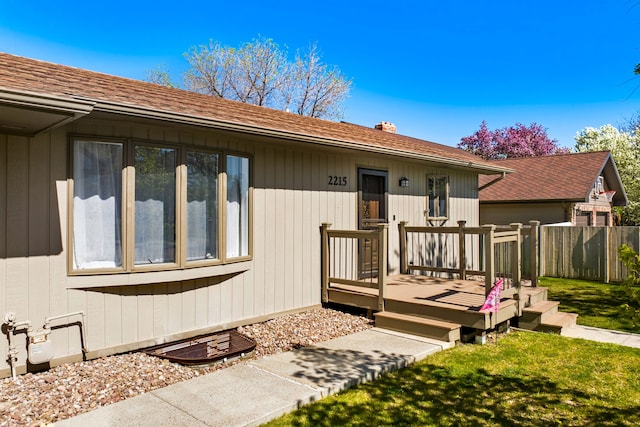 doorway to property with a wooden deck, a chimney, and a shingled roof