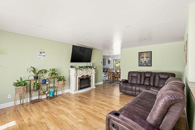 living room with light wood-type flooring, baseboards, and a glass covered fireplace
