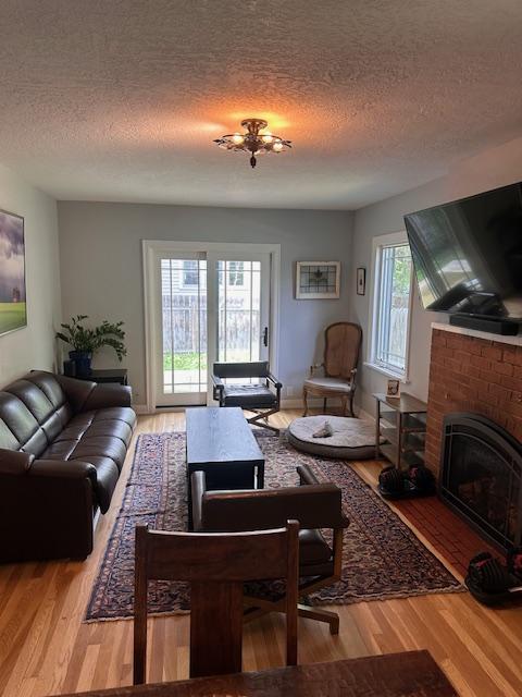 339 E Beckwith Ave, Missoula, MT 59801 - living room featuring light wood-style flooring, a textured ceiling, and a brick fireplace