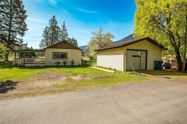 10225 Shady Ln, Bonner, MT 59823 - view of side of property featuring an outdoor structure, a detached garage, a lawn, a deck, and asphalt driveway