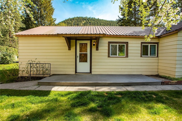 10225 Shady Ln, Bonner, MT 59823 - view of front of house featuring a wooden deck, a front lawn, and metal roof