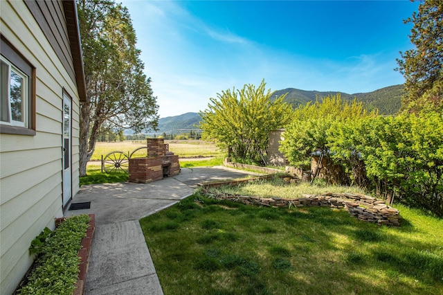 10225 Shady Ln, Bonner, MT 59823 - view of green lawn featuring a mountain view and a patio