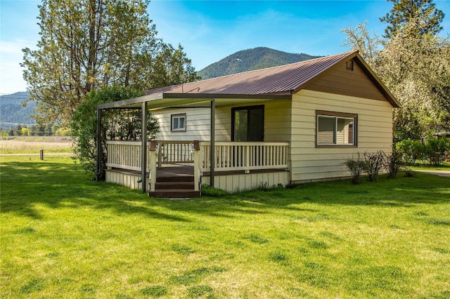10225 Shady Ln, Bonner, MT 59823 - rear view of property featuring a deck with mountain view, a lawn, and metal roof