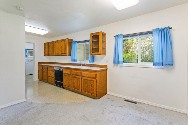 10225 Shady Ln, Bonner, MT 59823 - kitchen with black dishwasher, brown cabinetry, a sink, baseboards, and glass insert cabinets