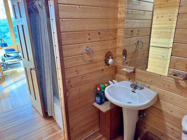 bathroom featuring wooden walls, wood finished floors, and a sink
