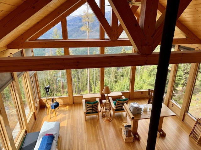 sunroom with healthy amount of natural light, wood finished floors, high vaulted ceiling, and beamed ceiling
