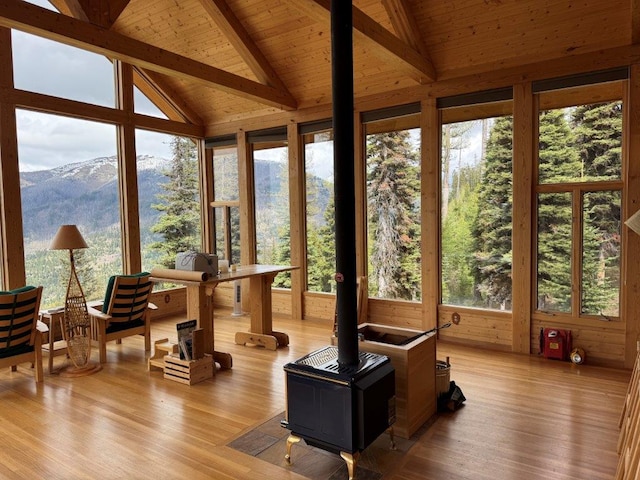 sunroom / solarium featuring a wood stove, wood finished floors, wooden ceiling, and a deck with mountain view