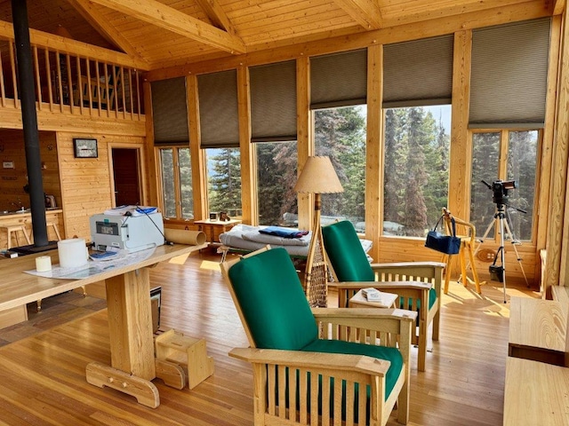 sunroom featuring healthy amount of natural light, wood ceiling, a wood stove, wood finished floors, and a deck