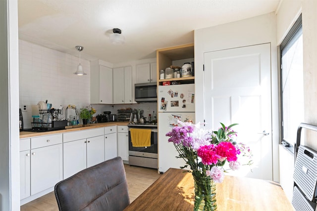 2112 W Central Ave, Missoula, MT 59801 - kitchen with appliances with stainless steel finishes, a sink, light wood-style floors, white cabinetry, and tasteful backsplash