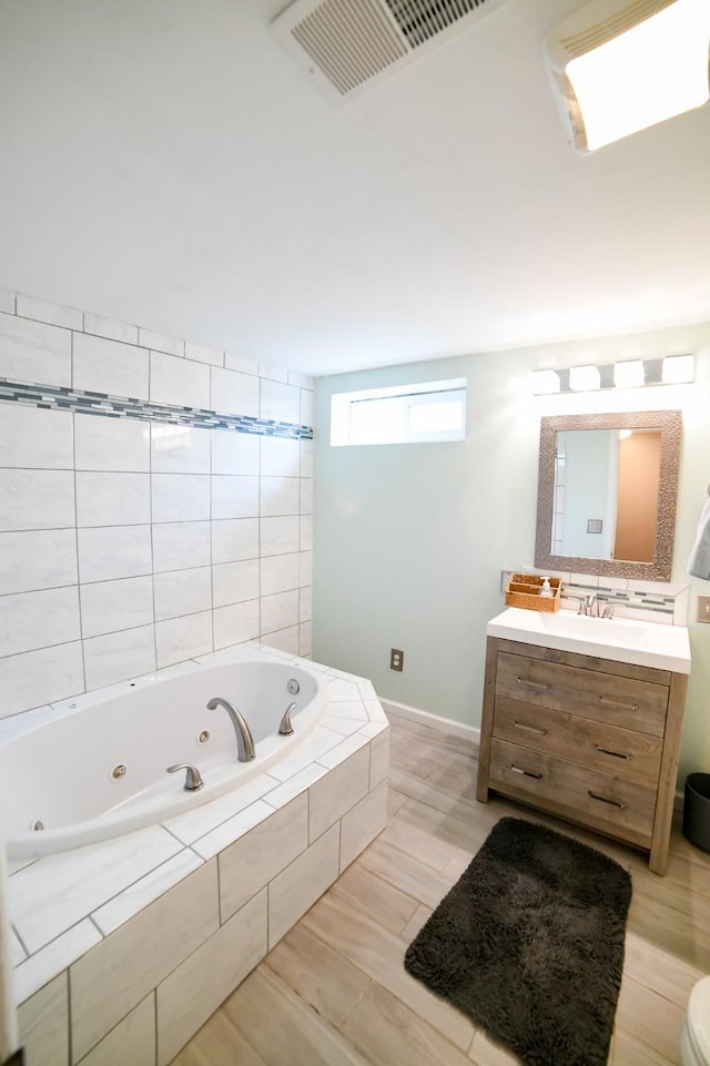full bathroom with a whirlpool tub, vanity, and baseboards