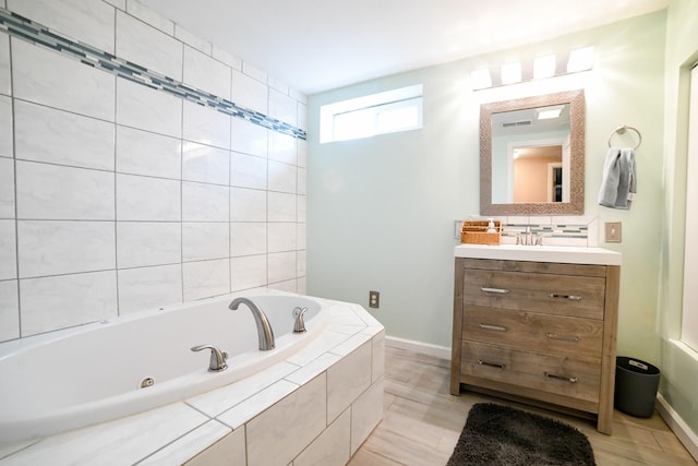 bathroom with a jetted tub, vanity, and baseboards