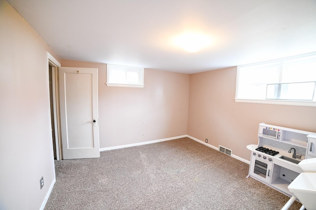 basement featuring carpet flooring, baseboards, and healthy amount of natural light