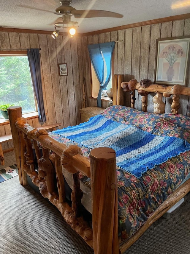 174 Badger Trl, Eureka, MT 59917 - bedroom with carpet, wooden walls, a textured ceiling, and a ceiling fan