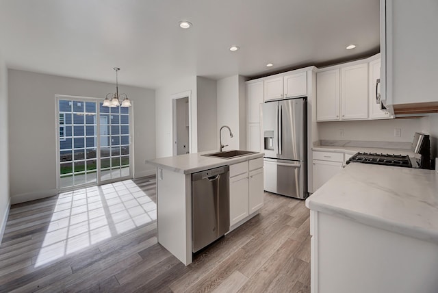 259 Stirling Loop, East Helena, MT 59635 - kitchen featuring appliances with stainless steel finishes, a chandelier, light wood finished floors, a kitchen island with sink, and white cabinetry