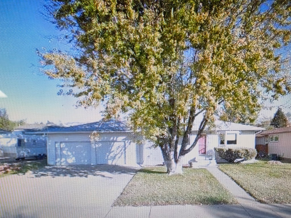 view of front of property featuring a garage, driveway, and a front lawn