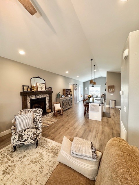 3975 Jaycee Ct Unit B, East Helena, MT 59635 - living room with lofted ceiling, light wood-type flooring, a stone fireplace, baseboards, and recessed lighting