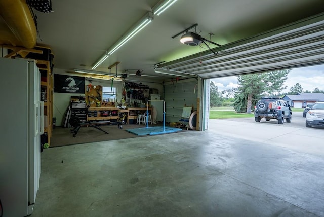 garage with freestanding refrigerator, a garage door opener, and a workshop area