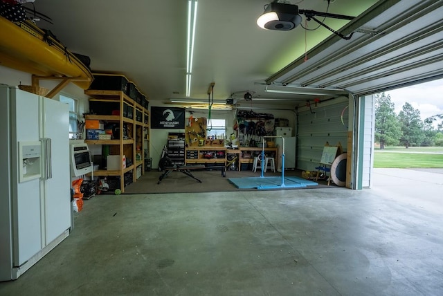 garage with white fridge with ice dispenser, refrigerator, a garage door opener, and a workshop area