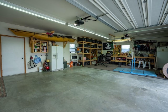 garage with white fridge with ice dispenser, a workshop area, and a garage door opener
