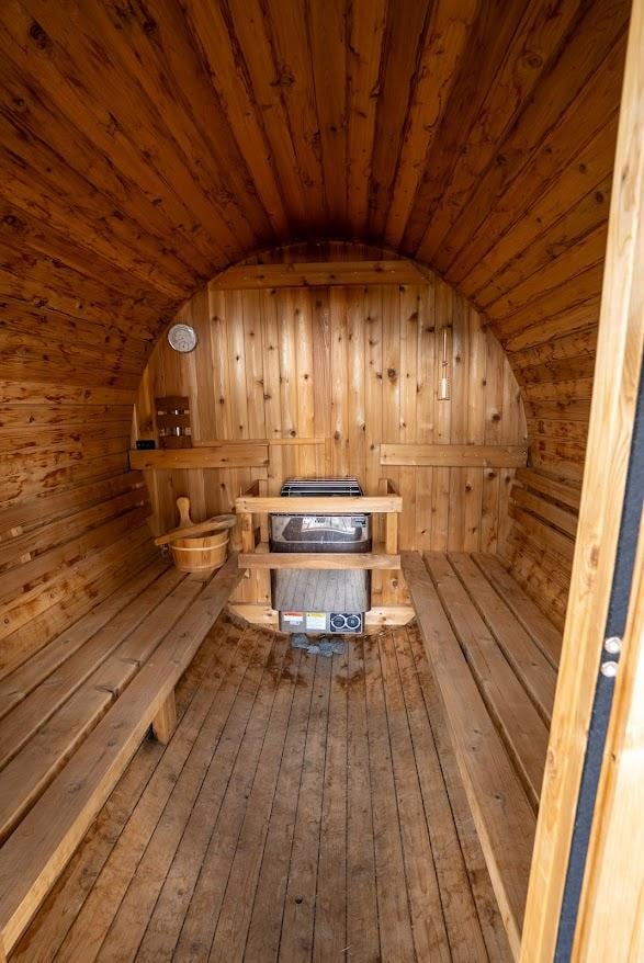 sauna with wooden ceiling, wood walls, and hardwood / wood-style flooring