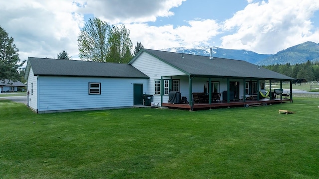back of house with a mountain view and a lawn