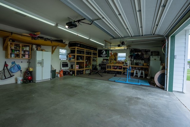 garage with a garage door opener, white refrigerator with ice dispenser, and a workshop area