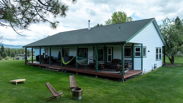 back of property with a lawn, a deck, and roof with shingles