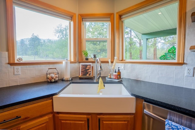kitchen with dishwasher, a sink, dark countertops, and tasteful backsplash