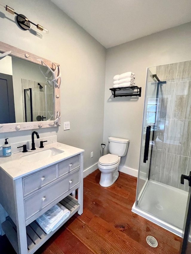 full bathroom with a shower stall, toilet, wood finished floors, vanity, and baseboards