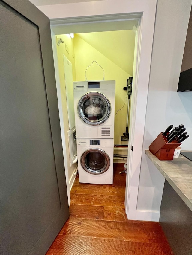 clothes washing area featuring estacked washer and dryer and wood finished floors